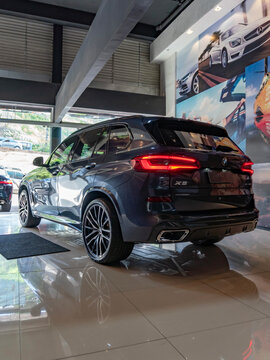 Dark grey BMW X5 rear three quarters view, Luxury SUV parked in indoor showroom