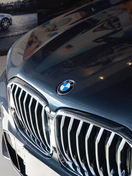 Dark grey BMW X5 hood emblem and front grille close up, Luxury SUV indoors logo with reflections