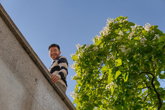 Smiling man looking over a stone wall in sunny park