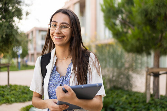 Smiling university student on campus holding a tablet