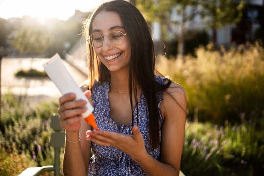 Woman applying sunscreen outdoors on sunny summer day