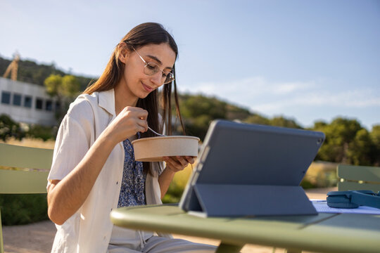 Student eating lunch and studying outdoors on campus