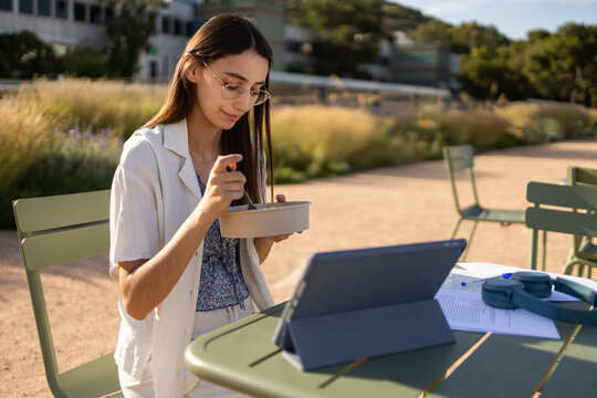 University student studying outdoors on campus with tablet
