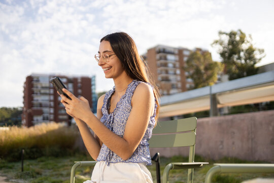 Young woman texting on smartphone in sunny city park