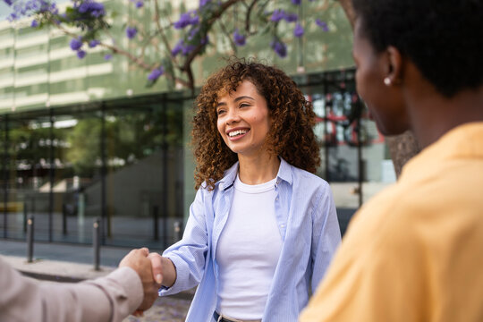 Smiling woman shaking hands outdoors in city setting
