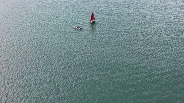 Aerial drone footage of two small boats sailing across vast open water, capturing the sense of scale, solitude, and tranquillity of the surrounding seascape on a bright day