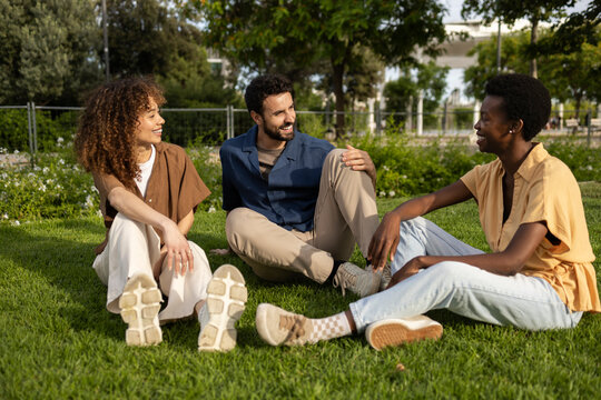 Friends chatting and relaxing together on green park grass