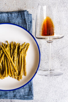 Fermented asparagus on enamel plate with glass on stone