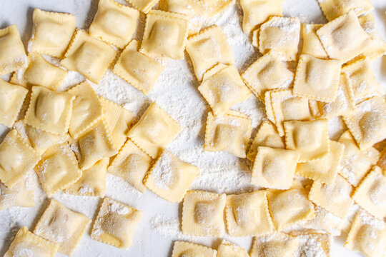 Homemade ravioli on floured surface, top view background