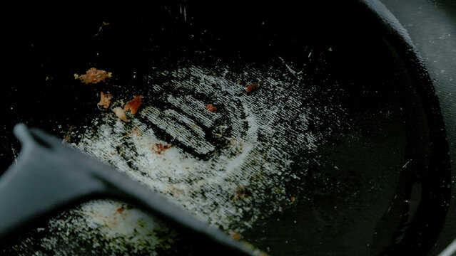 Close-Up of Worn Nonstick Teflon Frying Pan Being Scrubbed with Kitchen Utensil, Illustrating Cookware Safety and Potential Health Risks