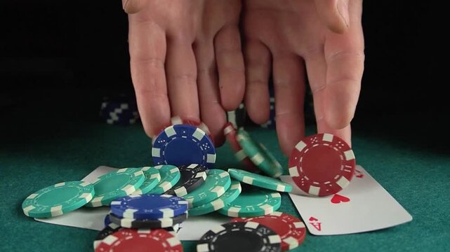 Hands dropping poker chips onto a green felt table with playing cards face up, showcasing a dynamic gambling scene in a casino environment
