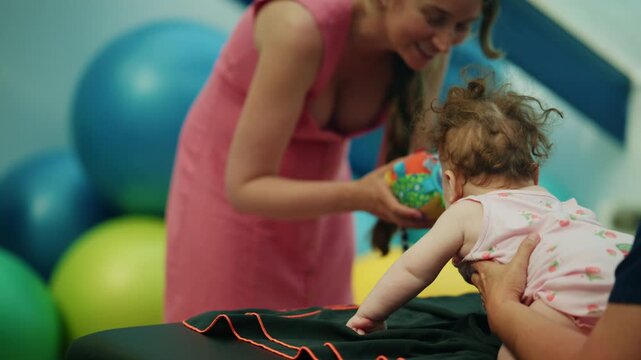 Mother and therapist working with a baby on developmental exercises. Child receiving physical therapy for health and wellness
