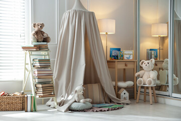 Beautiful wigwam, different toys and books in child's room. Interior design © New Africa