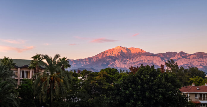 Antalya, Turkey - October 31, 2011: A beautiful panoramic viewpoint showcases Mount Olympos range glowing in pink pastel light during a serene early morning sunrise with resort villas