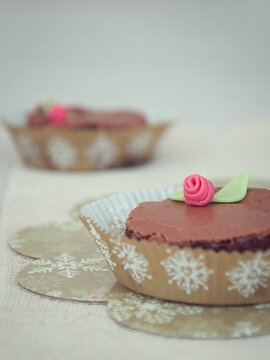 Close-up of two Chocolate Brownies in cupcake cases decorated with rose shaped fondant icing decorations