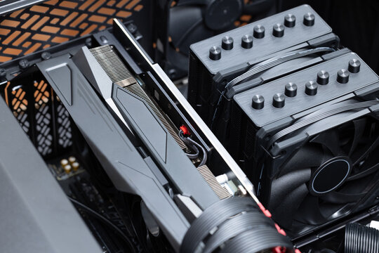 Open high-end gaming PC case with a large powerful graphics card. Dual tower air CPU cooler with two fans is installed. Expensive powerful computer components