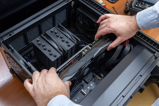 A technician installs a powerful graphics card in a desktop PC case. Desktop PC upgrade or assembly. Computer components