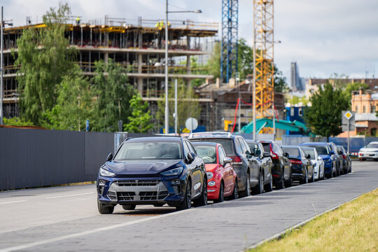 Parked automobiles on a city roadside near a large multi-story construction site highlighting urban development and real estate growth