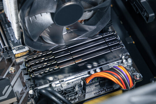 Close-up of four DDR RAM modules on a computer motherboard. Expensive PC components. CPU cooler fan is visible. Assembly or upgrade of a modern PC
