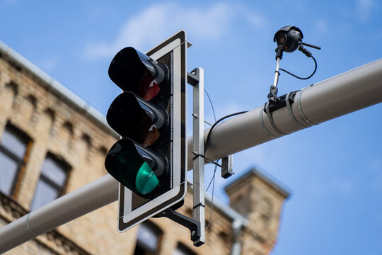 Green traffic light signal with a modern sensor dome camera mounted on a metal support pole representing intelligent traffic systems
