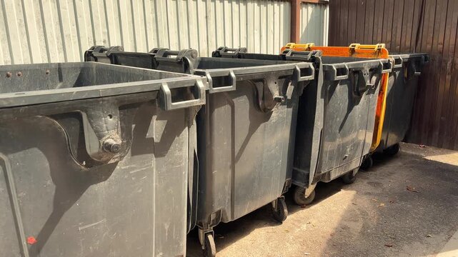 Large Black Waste Containers Lined Up Outdoors at Recycling and Garbage Collection Site