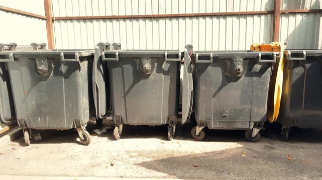 Large Black Waste Containers Lined Up Outdoors at Recycling and Garbage Collection Site