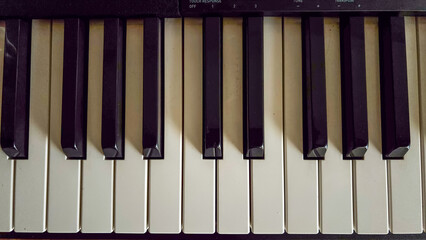 Top-down horizontal view of black and white digital piano keys in a flat lay symmetric composition. Sharp technical focus and uniform diffused lighting. © niltonemaia
