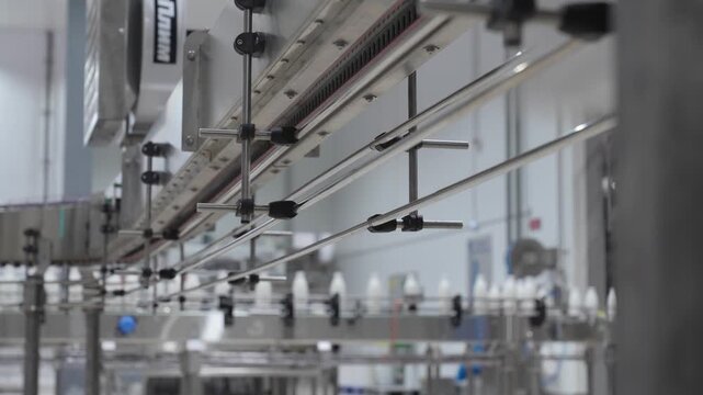 Elevated metal conveyor system transporting empty plastic bottles in a manufacturing plant