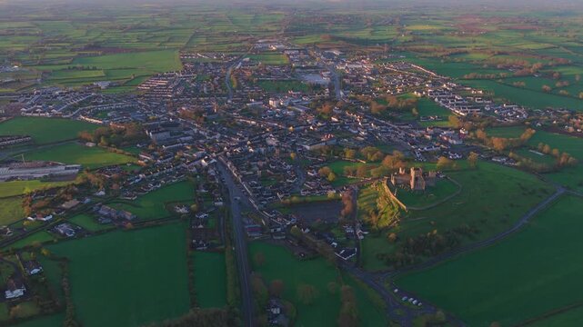 Aerial pullback over Cashel town and Rock of Cashel at golden hour, Ireland