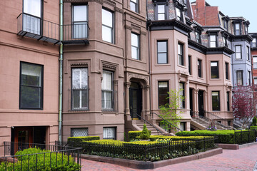 Naklejka premium Row of old brownstone townhouses with bay windows and small front gardens