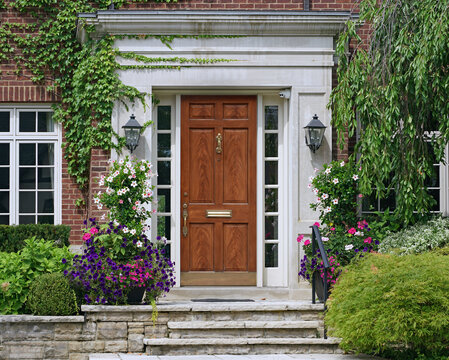 Home with elegant wood grain front door surrounded by flowers