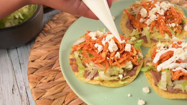 Preparing Mexican food. Chef putting sour cream on top of a crispy chicken tostada. Slow motion video