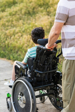 Grandfather pushing child in wheelchair outdoors