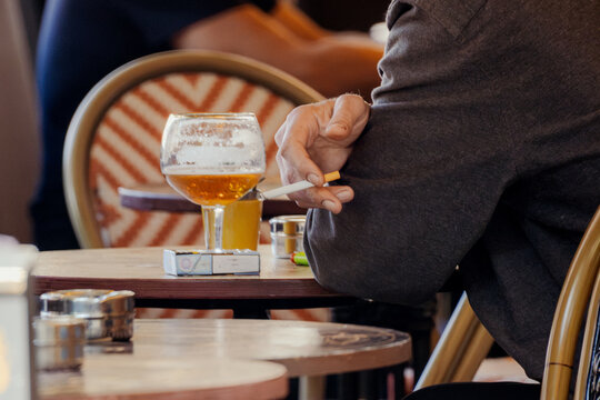 Man Smoking Cigarette and Drinking Beer at Outdoor Cafe