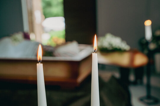 Burning funeral candles with blurred coffin in chapel background