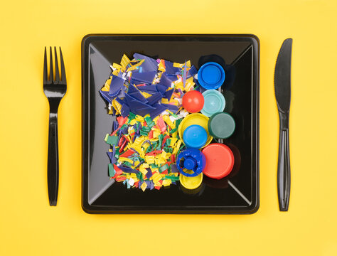 Plastic waste on a plate with fork and knife. Food containing plastic concept