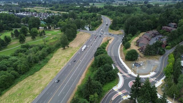 Heavy vehicle flow along Kent Des Moines Road cuts through rolling landscapes near manicured golf fairways. Overhead framing portrays the scenic interaction between active transit lanes and in WA