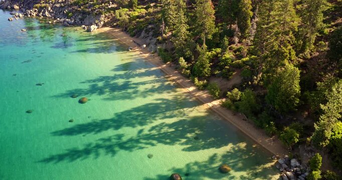 Lake Tahoe USA - Dramatic Pullback / Pan Shot of East Shore Beach with Clear Waters Sandy Beach and Shadows from Pine Trees