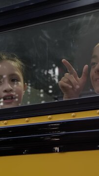 Kids pointing out the bus window at school