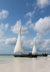 Tradycyjne drewniane łodzie z białymi żaglami na plaży Zanzibaru Tanzania © kubikactive