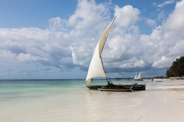 Tradycyjne drewniane łodzie z białymi żaglami na plaży Zanzibaru Tanzania © kubikactive