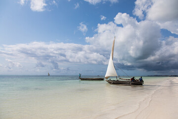 Tradycyjne drewniane łodzie z białymi żaglami na plaży Zanzibaru Tanzania © kubikactive