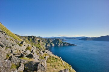 Fototapeta premium Breathtaking coastal landscape with steep rocky cliffs and deep blue ocean under a clear sky