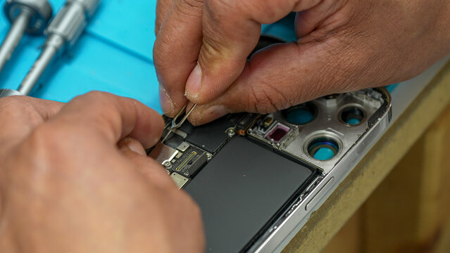 Close-up view of disassembled smartphone revealing internal motherboard components in repair lab