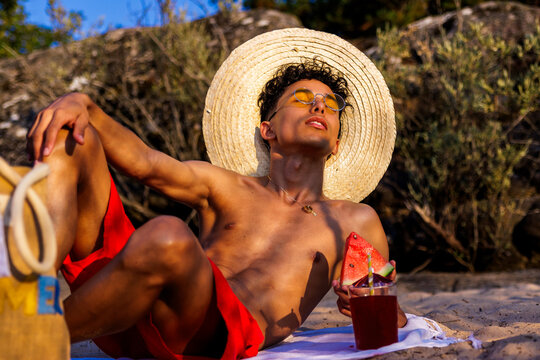 Young man relaxing on beach, enjoying summer sun and fresh watermelon