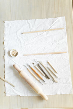 Creative clay pot on worktable with wooden handles and cloth, top-down