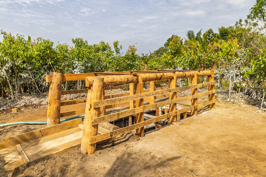 Gemstone mine in Sri Lanka, Rustic wooden bridge or animal chute in an outdoor farming or rural setting, surrounded by lush green foliage under a bright sky. Sri Lanka island in Asia.