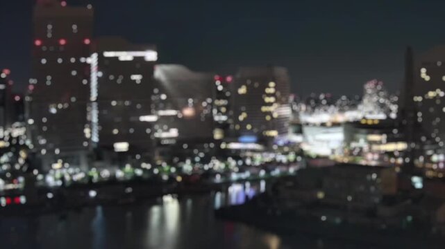 Defocused night timelapse of Yokohama skyline lights and reflections on the waterfront in Japan, creating a soft bokeh cityscape background.