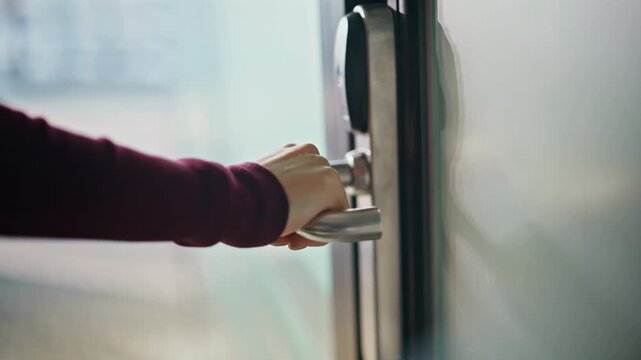 Closeup female hand opening glass office door. Business woman entering room