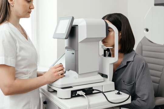 Female patient undergoing automated eye examination with an autorefractor under the supervision of an optometrist in a modern ophthalmology clinic